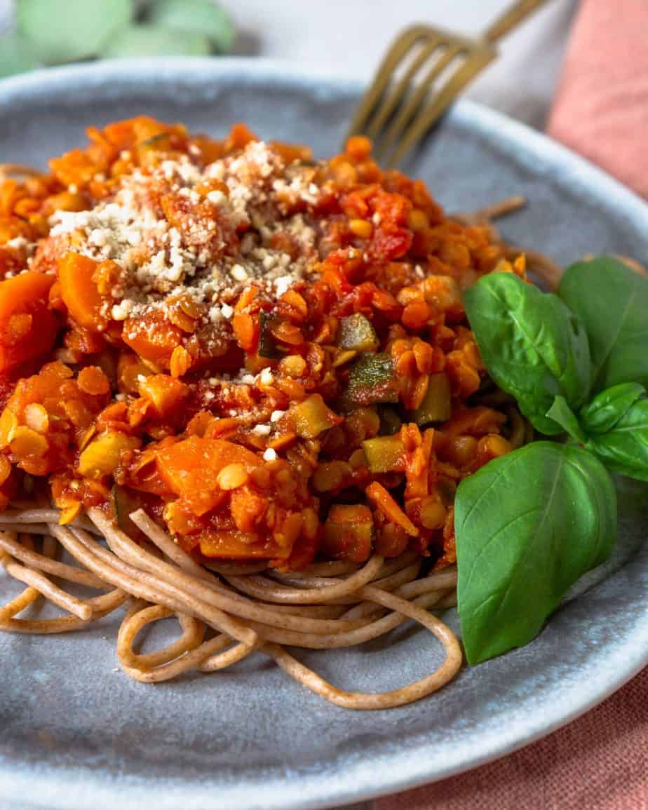 Teller mit Pasta und Bolognese aus roten Linsen seitlich